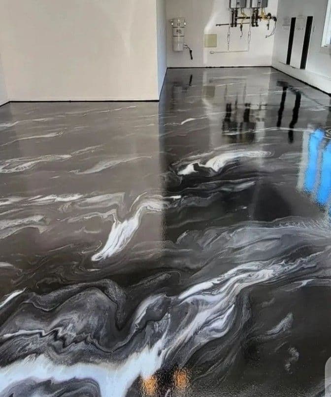 A high-gloss dark grey and black metallic epoxy floor with white marble-like swirls in a utility room.